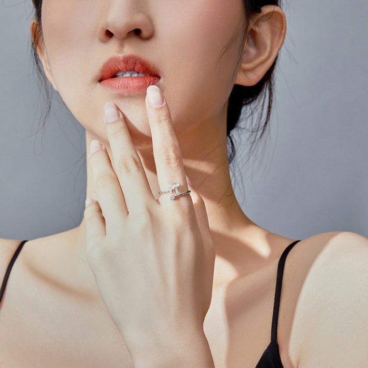 Close-up of woman wearing an open silver airplane zircon ring on her finger