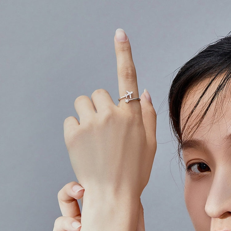 Woman showing an open silver airplane zircon ring on a raised hand