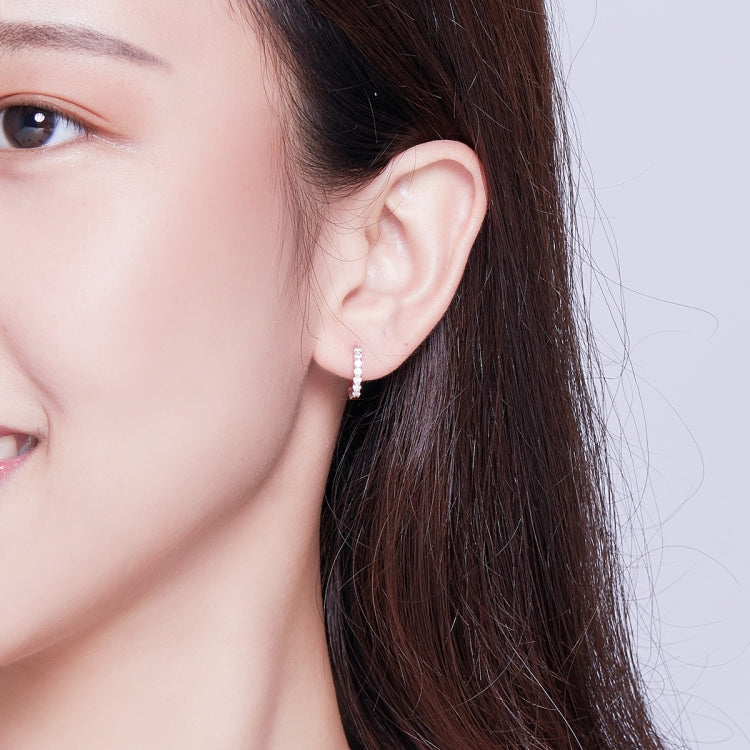 Rose gold small hoop earrings with zircon-like stones, worn on ear