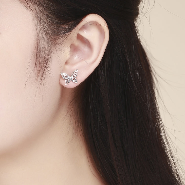 Sterling silver butterfly stud earrings on ear, showing polished wing cutouts