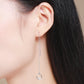 Sterling silver drop earring on ear with round crystal charm at chain end.