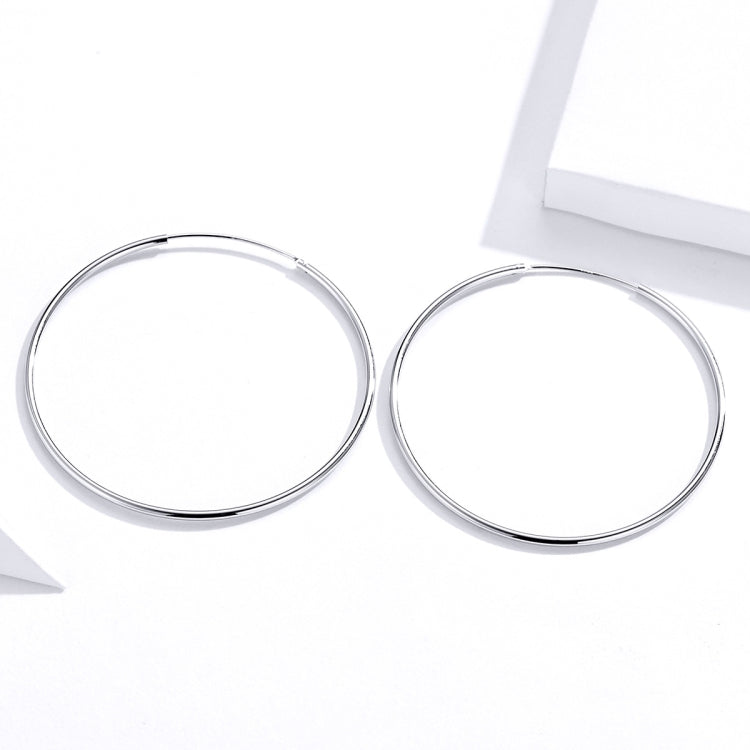 Silver-tone large oval hoop earrings with hinged clasp, angled view