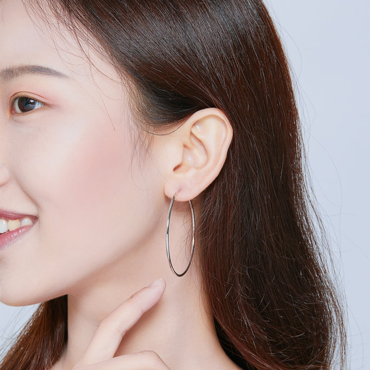 Large oval hoop earrings worn on ear, silver-tone finish