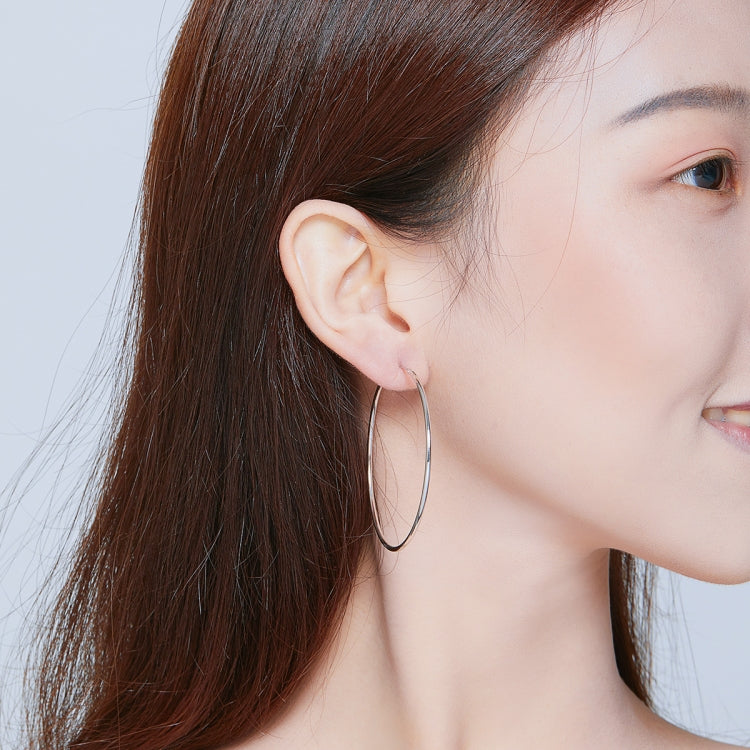 Silver-tone oval hoop earrings on ear, large hinged hoop profile