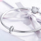 Sterling silver zircon bead charm on a coiled bracelet with bow ribbon
