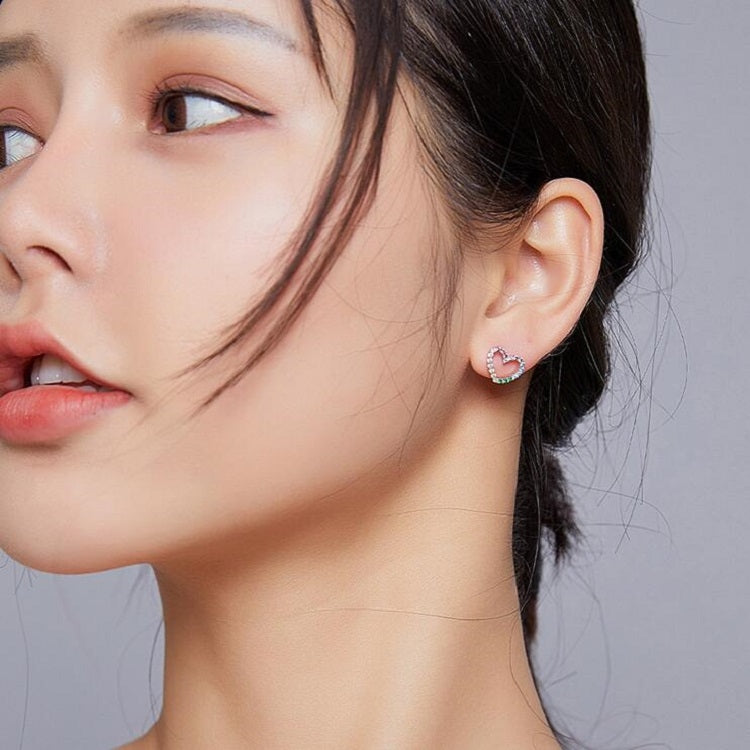 Model wearing heart-shaped rainbow CZ stud earrings in silver
