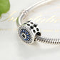 Silver bracelet with evil-eye charm bead, blue crystal ring, clear stones, black center