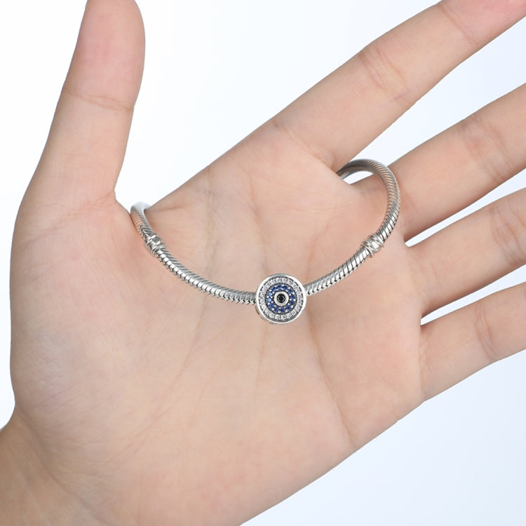 Evil-eye charm bead on silver bracelet on hand, blue crystals with black center