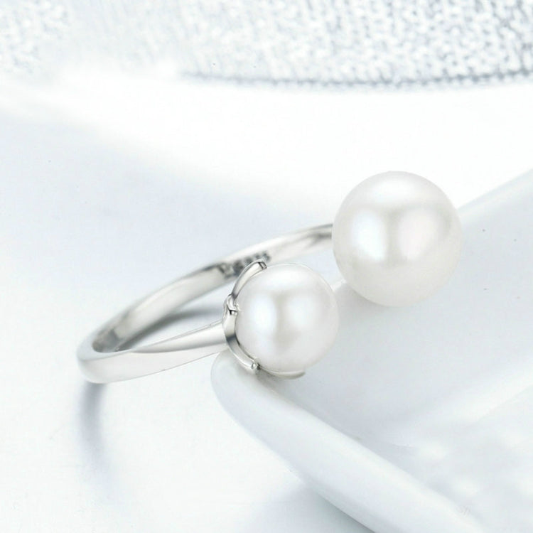 Open silver ring with two round white pearl-style stones on the band