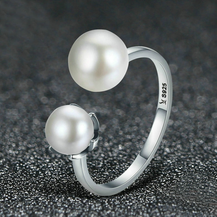 Open sterling silver ring with two round white pearl-style cabochons, side settings