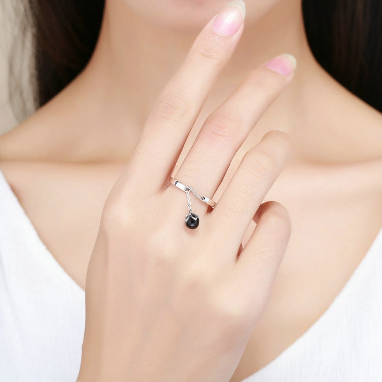 Sterling silver open ring with black pearl charm on finger, close-up hand view