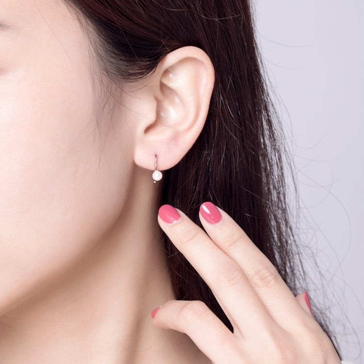 Rose gold hoop earrings with white pearl bead, worn by a model