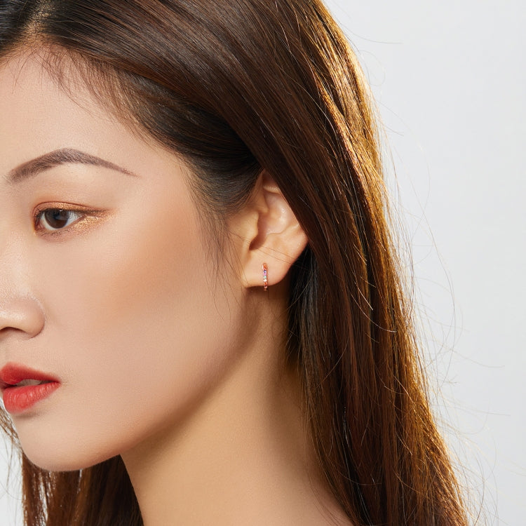 Rainbow zircon hoop earrings in rose gold, worn on model’s ear