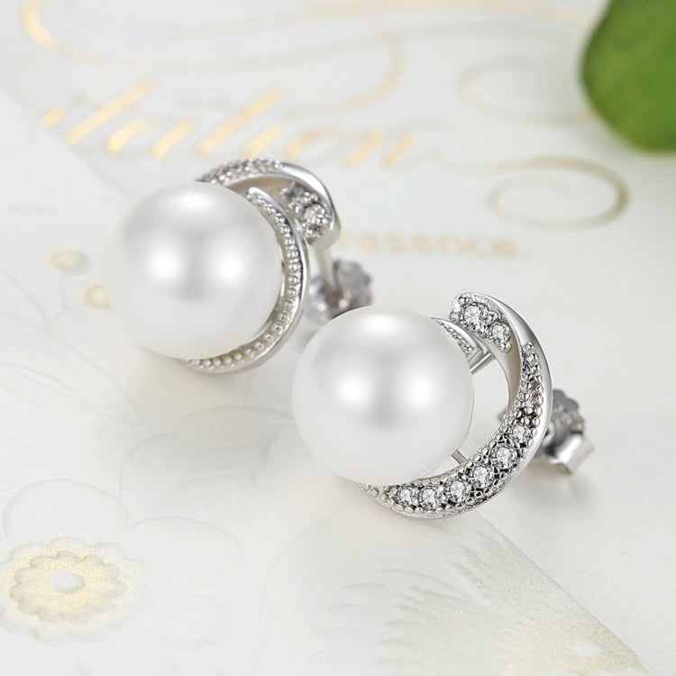 Close-up of white pearl stud earrings with silver round halo of small stones