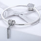 Heart-shaped silver bead charm on a silver bracelet with a hanging chain tassel