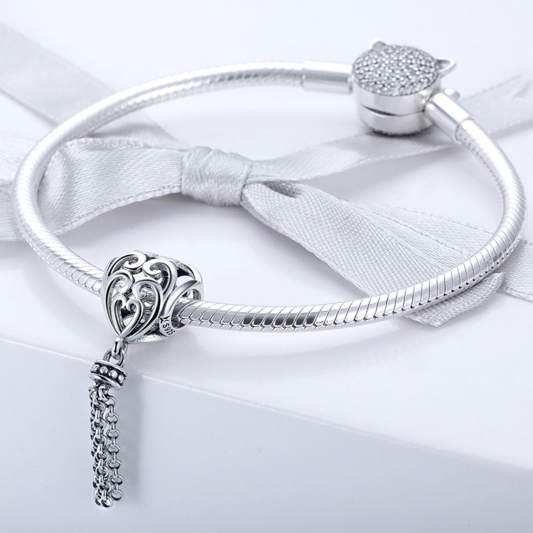 Heart-shaped silver bead charm on a silver bracelet with a hanging chain tassel