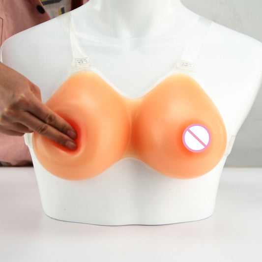 Silicone prosthetic breasts with clear straps on mannequin bust, hand adjusting