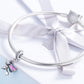 Sterling silver charm bracelet with witch broom charms, shown with white ribbon bow