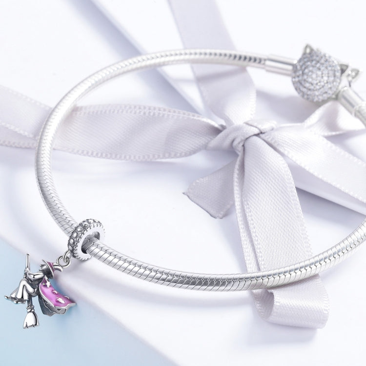 Sterling silver charm bracelet with witch broom charms, shown with white ribbon bow