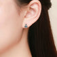 Robot earrings on ear: blue enamel heart panel with red accents on silver studs