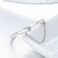 Close-up of silver open ring with round CZ stone, chain across band, prong setting