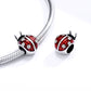 Ladybug charm bead with red enamel on a silver snake bracelet strand