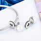 Silver charm bracelet with white pearl beads, crystal flower charms, and clasp