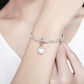 Sterling silver charm bracelet on wrist with white pearl drop pendant