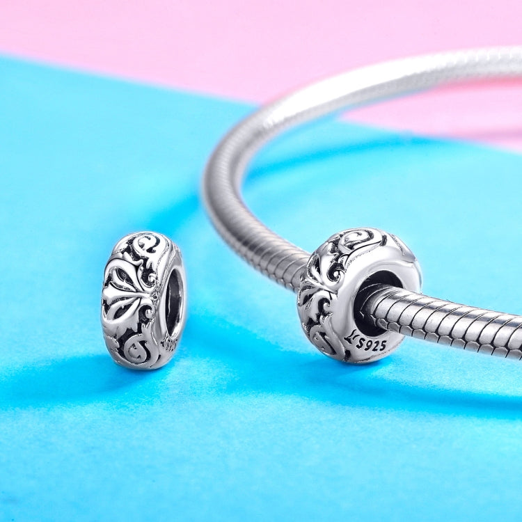 Two sterling silver flower-pattern bead charms on a silver bracelet chain