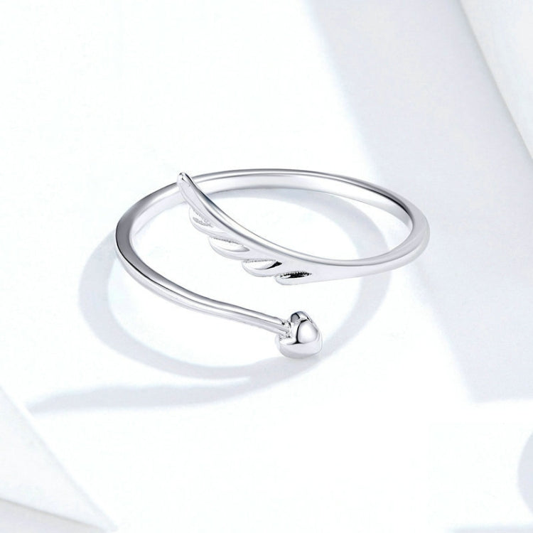 Silver open ring with angel wings detail and small lower charm, side view