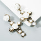 Pair of white rose cross earrings with gold-tone links and black rhinestone clusters