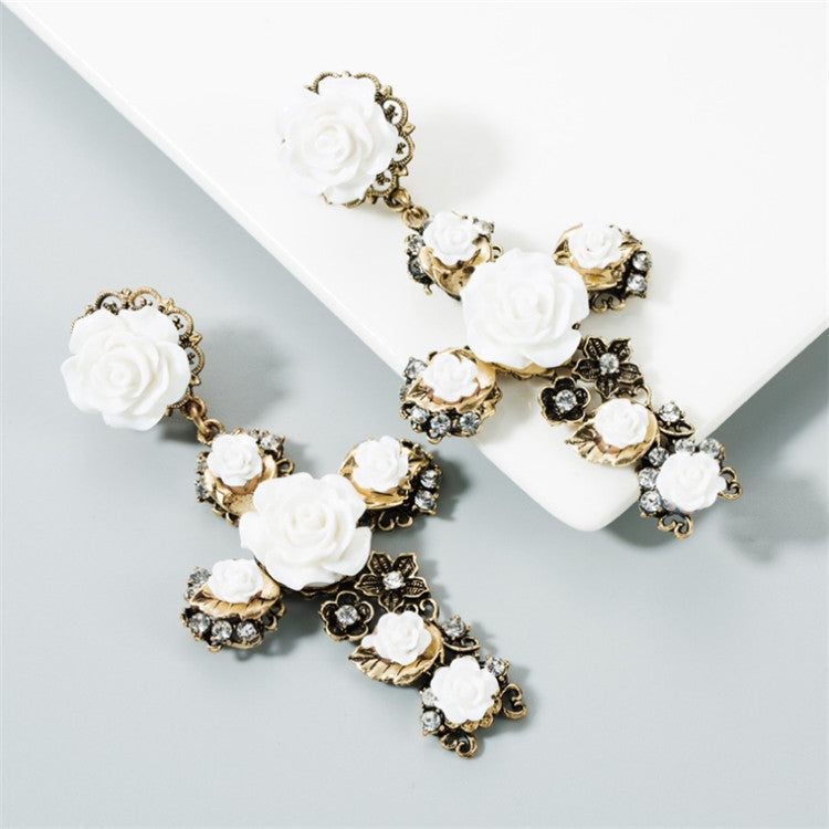 Pair of white rose cross earrings with gold-tone links and black rhinestone clusters