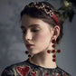 Model wearing red rose cross drop earrings with gold-tone and rhinestone details