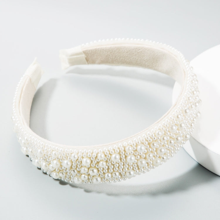 White pearl headband with beige inner band on a display, wide decorative crown.