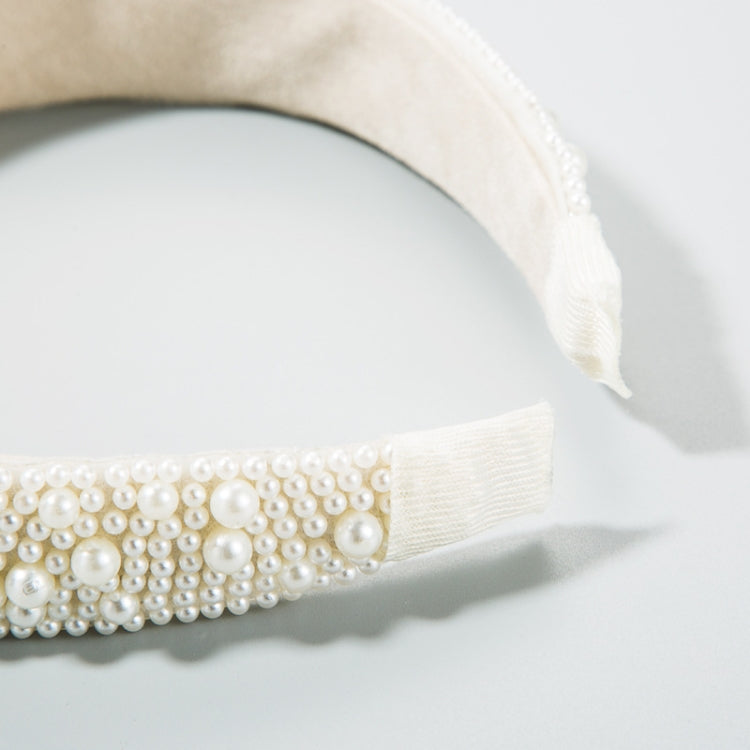 Close-up of white pearl beaded band with cream fabric backing and stitched end.