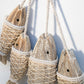 Cluster of hanging wooden fish ornaments with carved heads and twine netting