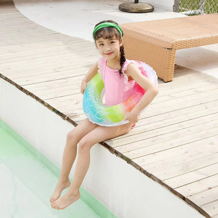 Child wearing a rainbow gradient PVC swimming ring on inflatable pool ramp
