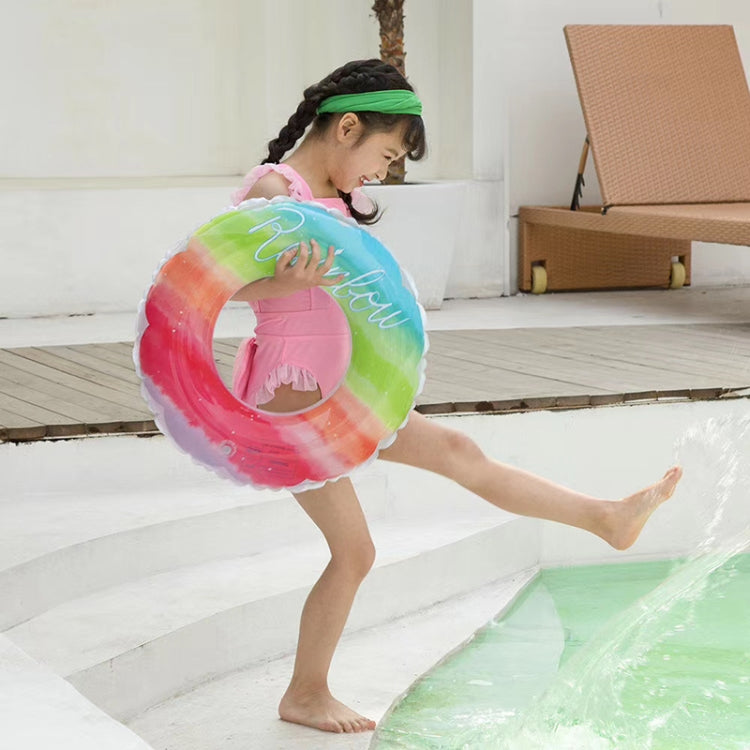 Child using a rainbow gradient PVC swimming ring while standing in pool water