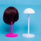 Wig on a pink stand and matching white wig display stand with dome head