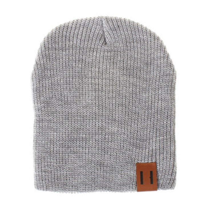 Gray knit baby beanie with folded cuff and leather patch label on side