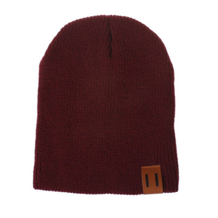 Dark red knit baby beanie with folded cuff and square leather patch label