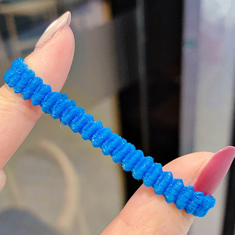Blue rubber hair band, small loop tie held on a fingertip