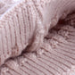 Light pink knit beanie fabric close-up with ribbed texture and soft faux-fur pom pom