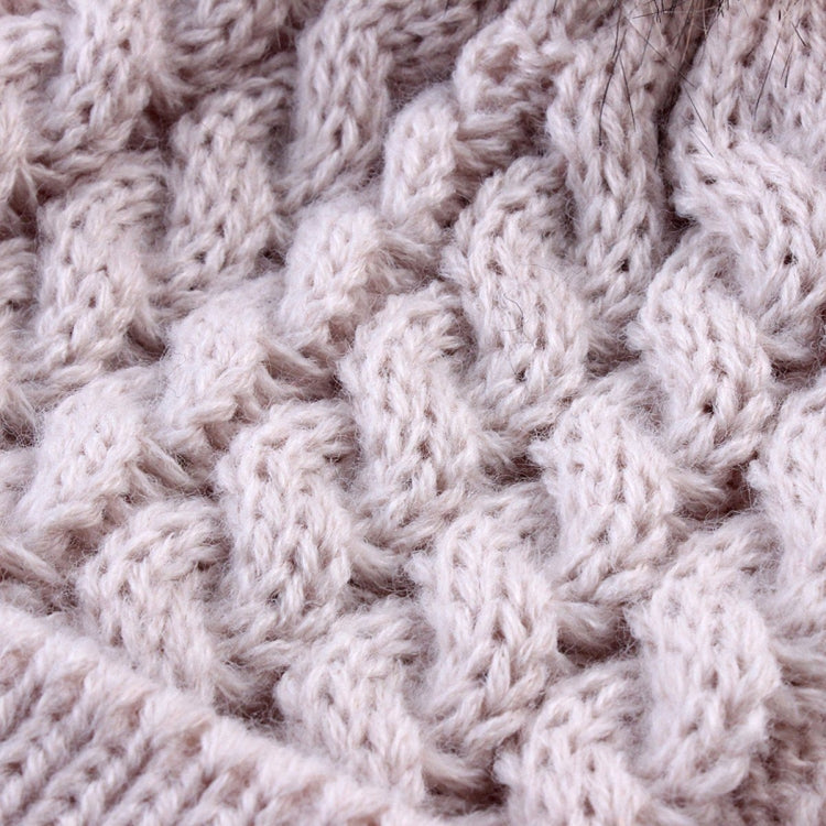 Cream knit beanie fabric close-up with raised cable pattern and cozy ribbed brim
