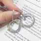 Silver-tone round rhinestone hoop earrings with small top ring, held by fingers