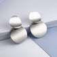 Silver-tone round drop earrings with three curved discs, shown from the side.