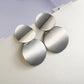 Silver-tone round drop earrings with three stacked discs and hook backs.