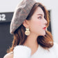 Gold-tone round drop earrings with two stacked discs, worn on the ear.