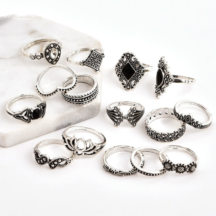 Silver-tone decorative ring set with floral and lotus motifs and black gemstone details