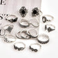 Assorted silver-tone rings with black stones and filigree details, scattered on a surface